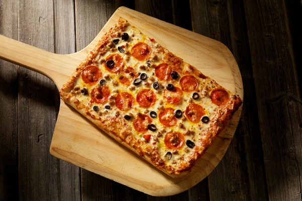 rectangular pepperoni pizza on a large wooden pizza spatula