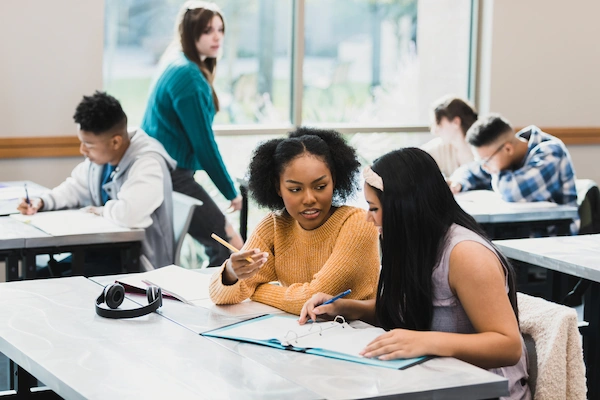 two female students working together at their desk to solve a math problem