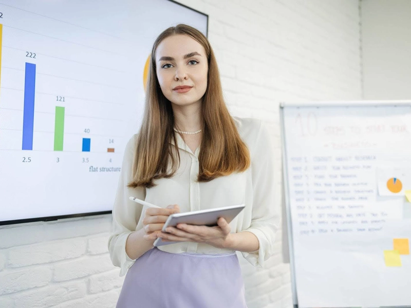 A statistics tutor in front of a whiteboard of info diagrams and bars